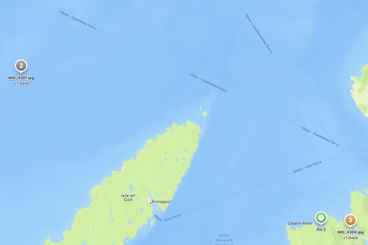 Map view showing two photos clustered in the open Sea of the Hebrides — an obviously wrong GPS location — with a corrective pin dropped on the Calgary Bay beach on the Isle of Mull where they actually belong