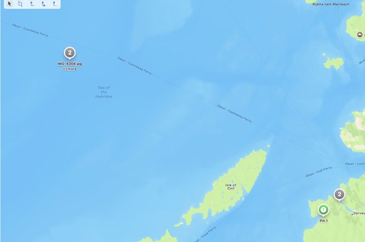 Map view showing two photos clustered in the open Sea of the Hebrides — an obviously wrong GPS location — with a corrective pin dropped on the Calgary Bay beach on the Isle of Mull where they actually belong